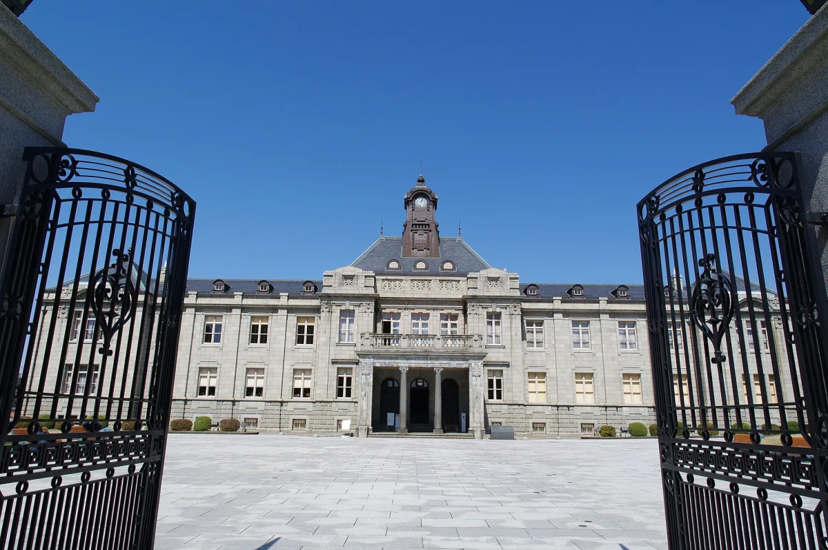 Stone facade and clock tower of Bunshokan, the former Yamagata prefectural office, seen through iron gates