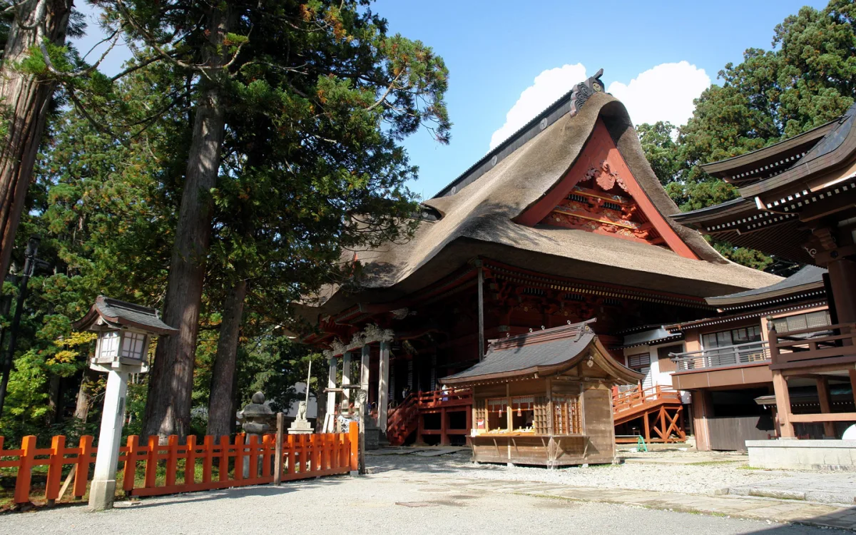 The thatched-roof Sanjin Gosaiden hall at the summit of Mount Haguro among tall cedars
