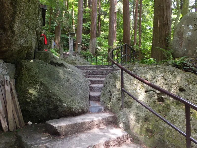 Stone stairway with handrail between large rocks on the approach to Okunoin, Yamadera