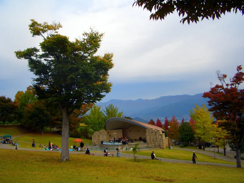 Lawns and autumn trees on the slopes of Fuefukigawa Fruit Park with mountains behind